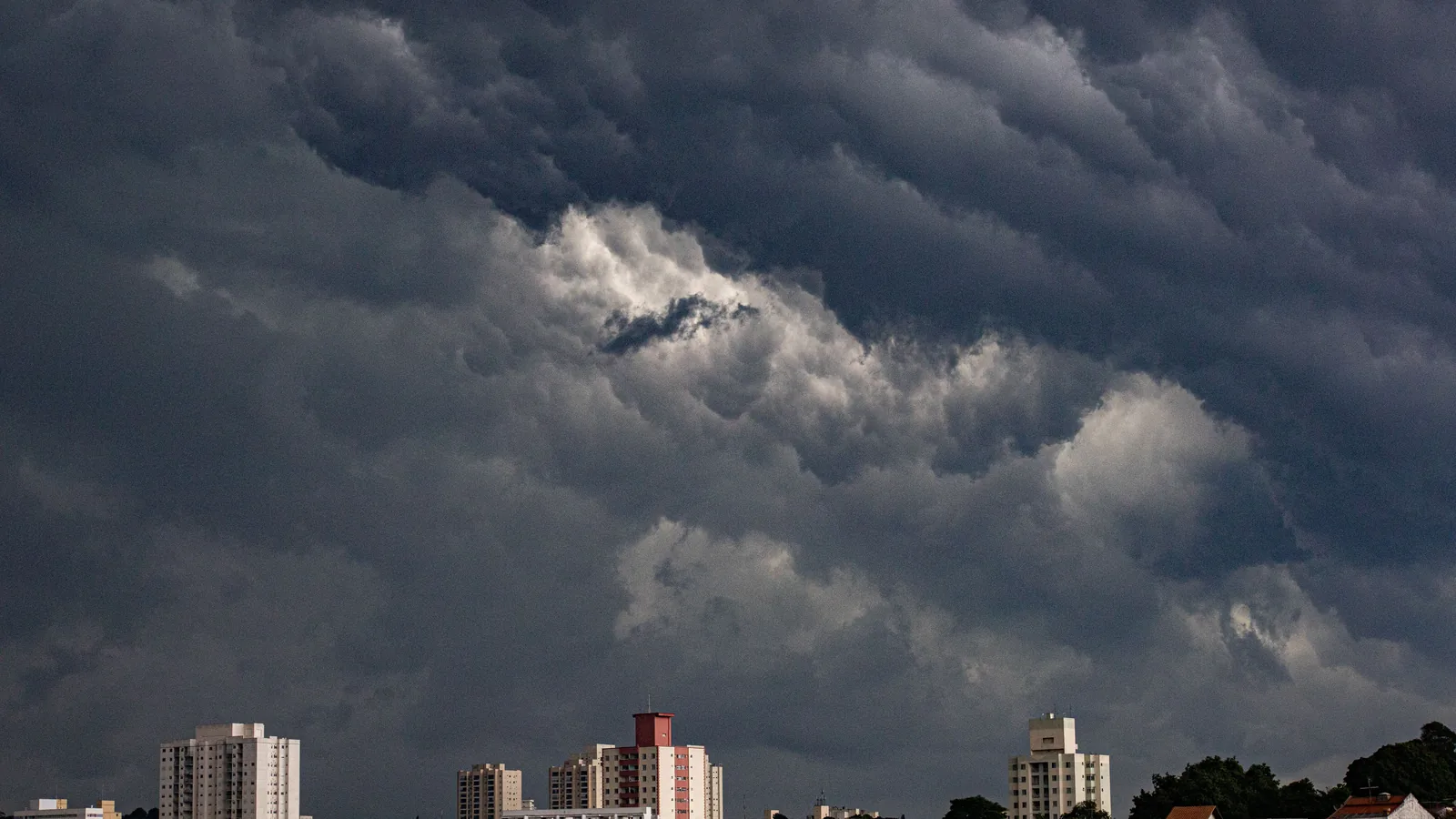 Dark storm clouds over apartment towers, with no readable city name