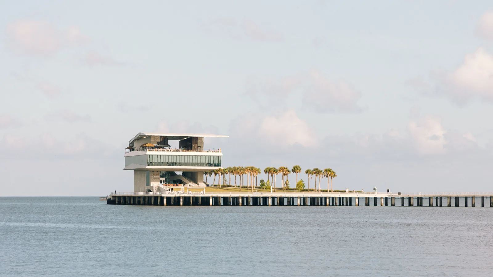 The St. Pete Pier head building and its row of palms at the end of the pier, over the calm water of Tampa Bay