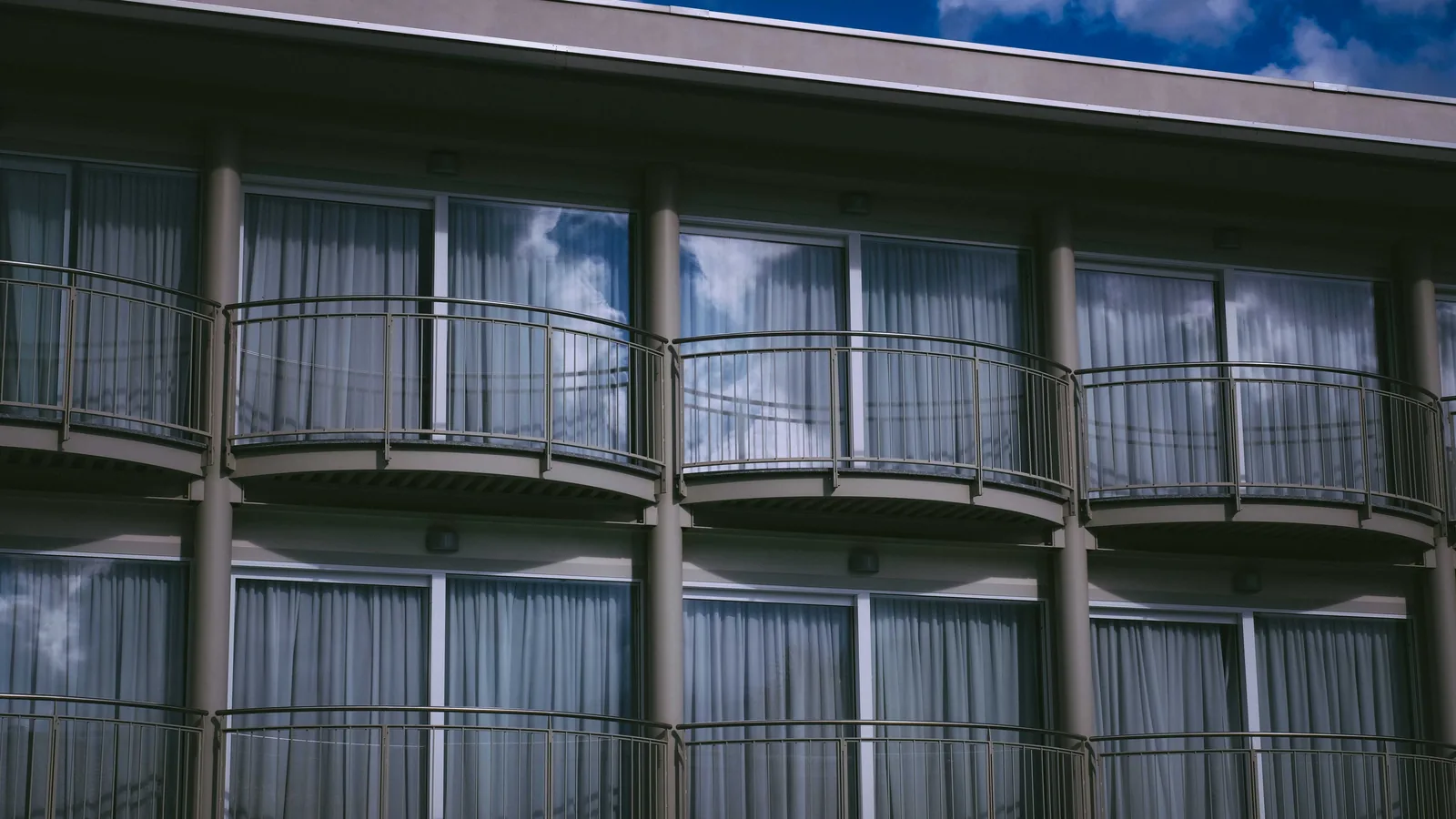 Glass doors behind curved balcony railings on a multi-story building