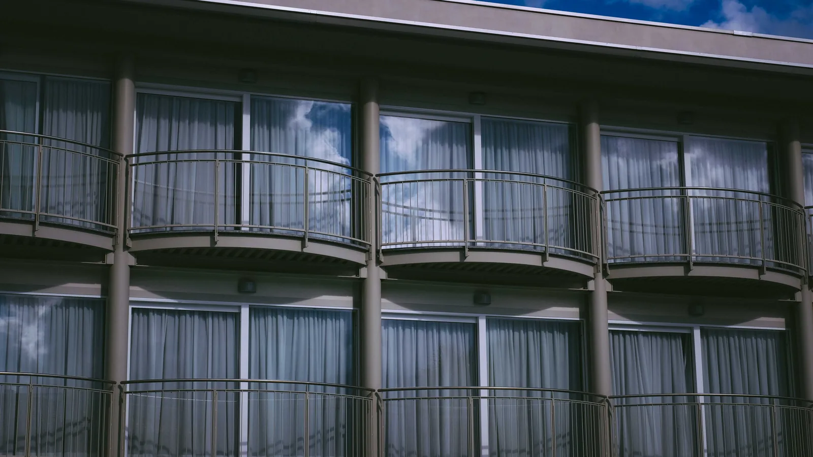 Curved metal-rail balconies and glass doors on a multi-story building