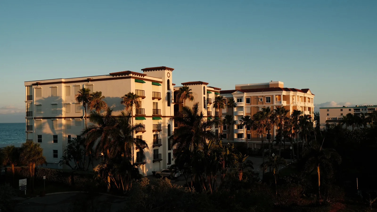 Palm-lined waterfront condo buildings at dusk