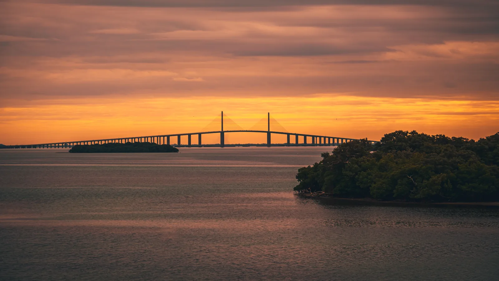 The Sunshine Skyway Bridge at sunset over Tampa Bay, with mangrove islands in the foreground